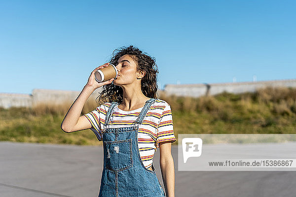 Young woman drinking coffee from a disposable cup