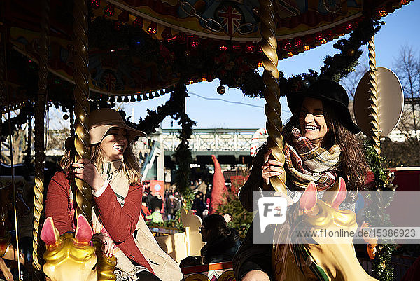 Two happy women having fun on a carousel