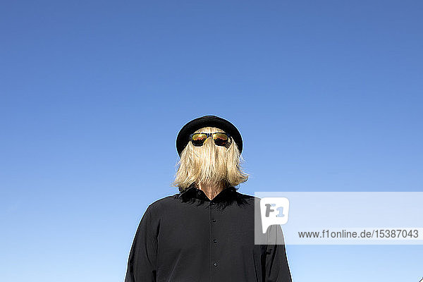 Blond hair covering man's face wearing sunglasses and bowler hat
