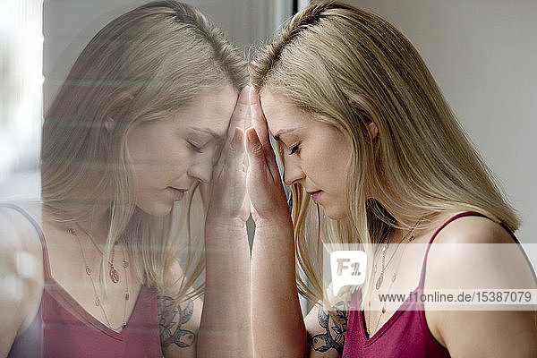 Profil einer blonden jungen Frau und ihre Reflexion über die Fensterscheibe