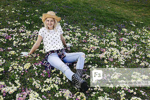 Junge Frau sitzt auf Blumenwiese