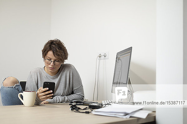 Junge Frau nutzt Smartphone zu Hause  am Arbeitsplatz