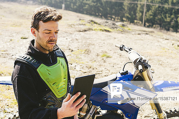 Portrait eines Motocross-Fahrers beim Blick auf das Tablet