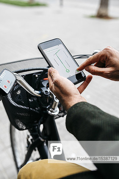 Nahaufnahme eines Mannes mit E-Bike und Smartphone-Navigationssystem