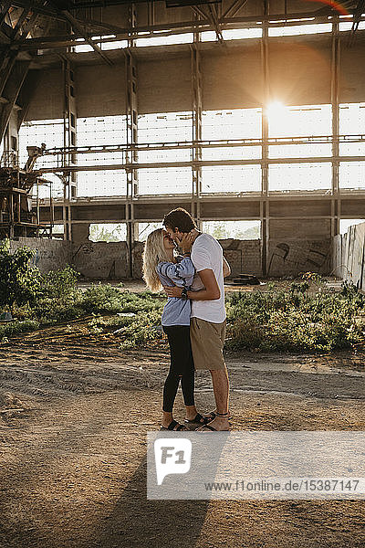Young couple kissing in an old hall at sunset