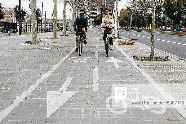 Ein Paar fährt in der Stadt auf dem Fahrradweg E-Bikes