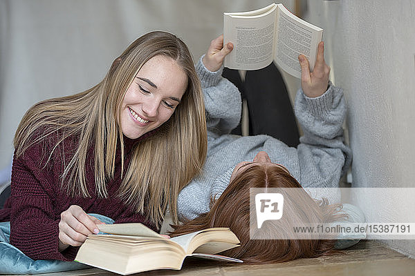 Zwei Freunde liegen nebeneinander auf dem Boden und lesen Bücher