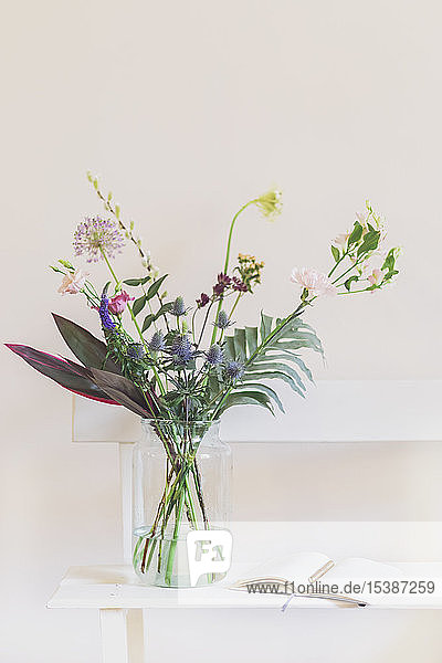 Flower vase and open calendar on white bench