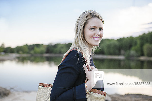 Porträt einer lächelnden blonden Frau an einem See