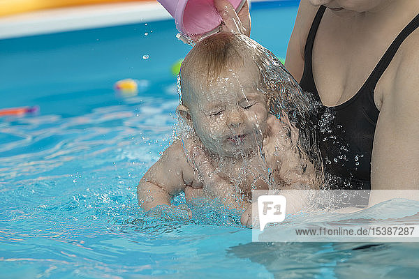 Babyschwimmen  Mutter mit Tochter im Schwimmbad  Mutter gießt Wasser über den Kopf