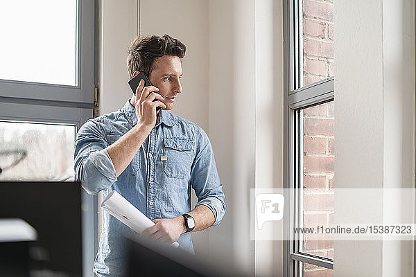 Businessman on cell phone at the window in office