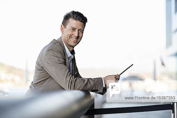 Smiling businessman with tablet standing outdoors