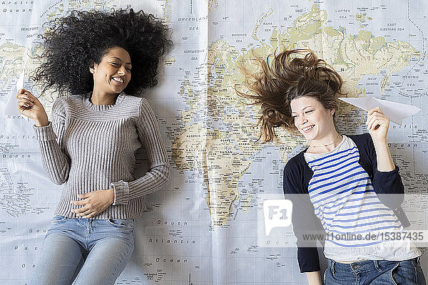 Freunde liegen auf der Karte  werfen mit Papierpalnen  planen ihren Urlaub