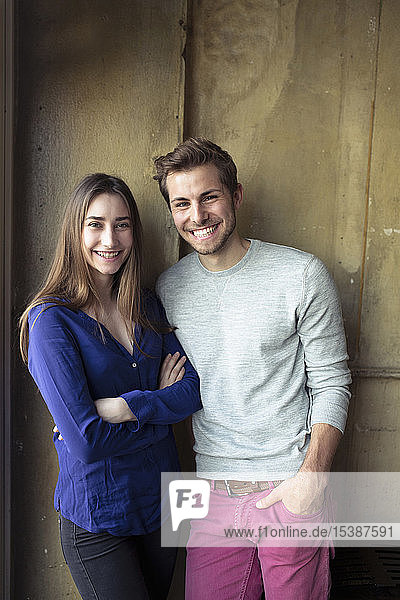 Portrait of happy young couple standing at a wall