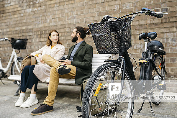Couple sitting on a bench next to e-bikes talking