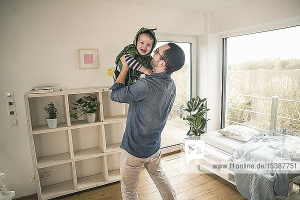 Father playing with happy son in a costume at home