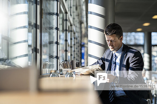 Businessman reading newspaper at the window in a cafe