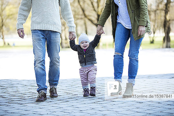 Portrait of girl walking hand in hand with parents