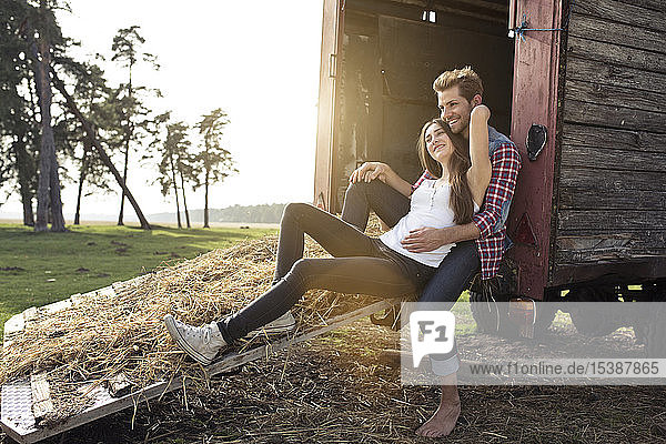 Glückliches junges Paar sitzt auf einem Wohnwagen auf dem Land