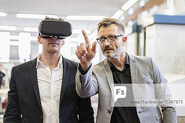 Two businessmen with VR glasses in factory