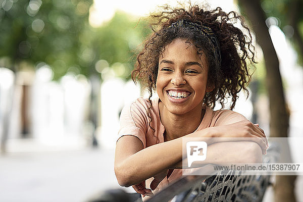 Porträt einer glücklichen jungen Frau auf einer Bank sitzend