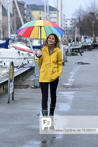 Dänemark  Kopenhagen  glückliche Frau mit buntem Regenschirm beim Spaziergang im Stadthafen