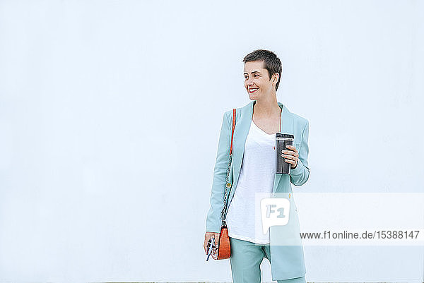 Frau in Anzugsjacke mit Thermobecher und Mobiltelefon  weißer Hintergrund