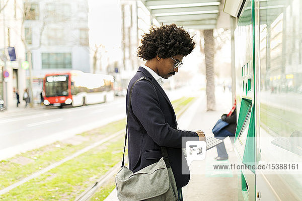 Spanien  Barcelona  Geschäftsmann benutzt Fahrkartenautomat an Straßenbahnhaltestelle in der Stadt