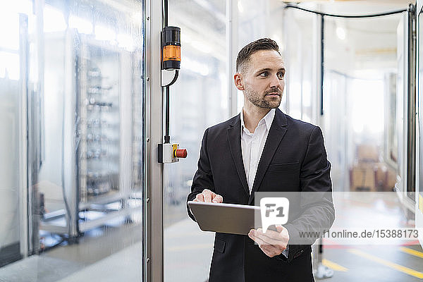 Geschäftsmann mit Tabletten in einer modernen Fabrik