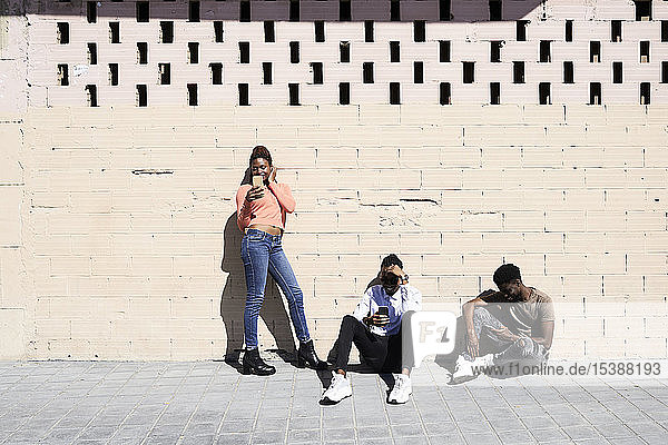 Drei Freunde  die im Freien Smartphones benutzen und sich gegenseitig ignorieren