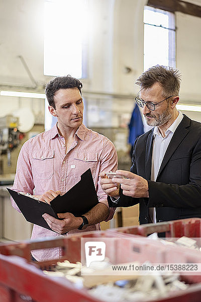 Zwei Männer in der Fabrik untersuchen Werkstück
