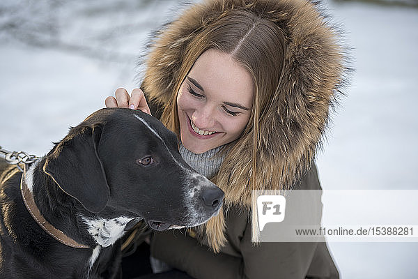 Happy young woman with dog in winter