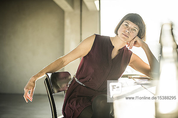 Pensive woman sitting in loft office