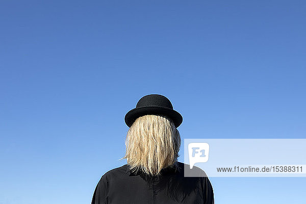 Blond hair covering man's face wearing bowler hat