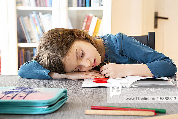 Schoolgirl napping at table with homework