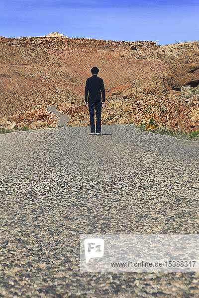 Morocco  Ounila Valley  rear view of man wearing a bowler hat standing on road in the mountains