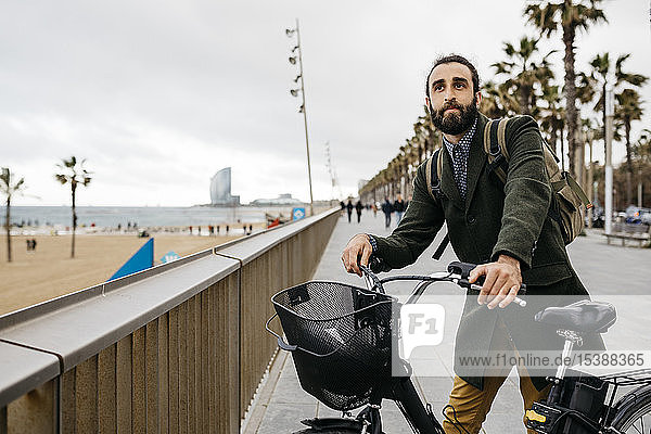 Mann mit E-Bike macht Pause an Strandpromenade