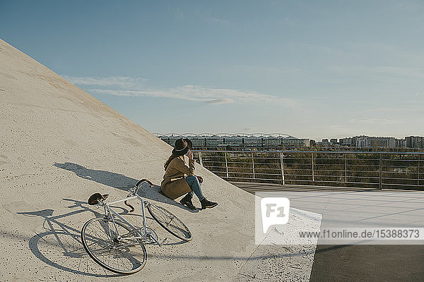Junge Hipster-Frau sitzt neben einem Fahrrad
