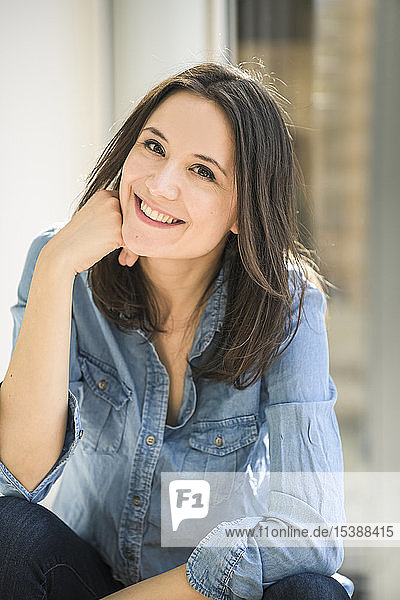 Porträt einer glücklichen Frau die zu Hause ein Jeanshemd trägt