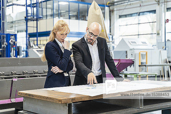 Geschäftsmann und Geschäftsfrau betrachten Plan auf dem Tisch in der Fabrik