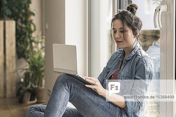 Woman sitting at the window at home using laptop