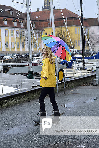Denmark  Copenhagen  happy woman with colourful umbrella strolling at city harbour