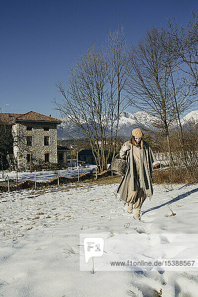 Italien  Limana  Frau mit Korb stolpert durch schneebedeckte Landschaft