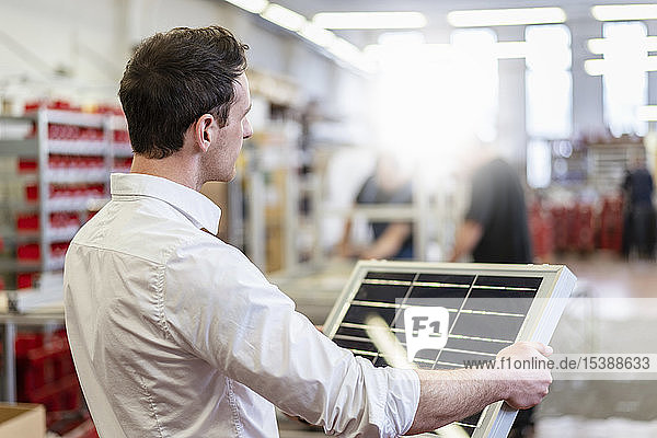 Mann in Fabrik mit Solarzelle