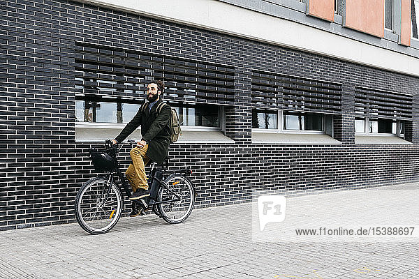 Mann fährt E-Bike entlang einer Ziegelmauer in der Stadt