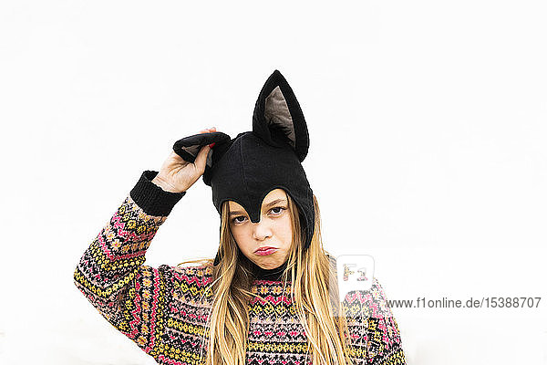 Portrait of displeased girl in bat costume in front of white wall