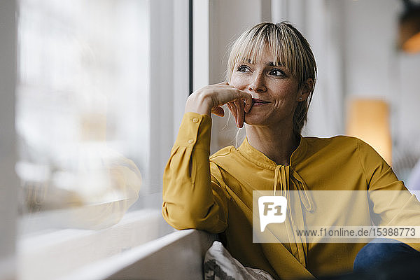 Porträt einer schönen blonden Frau  die aus dem Fenster schaut