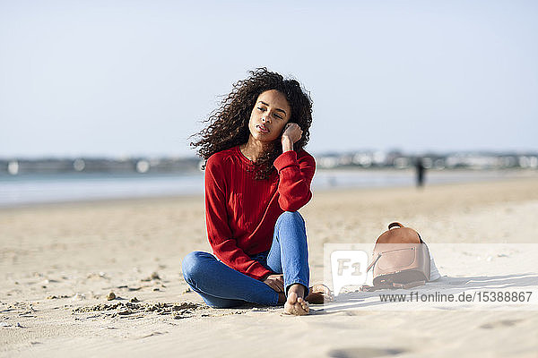 Thoughtful young woman sitting on the beach