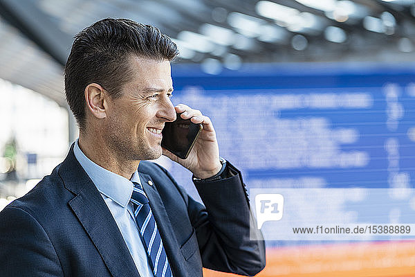 Smiling businessman on cell phone at the station