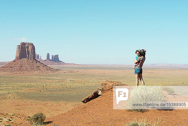 USA  Utah  Monument Valley  Mutter reist mit Mädchen  Mutter trägt Mädchen  stehend auf Aussichtspunkt